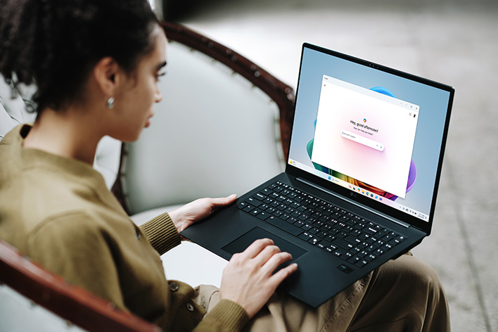 This image shows a person using a laptop, showcasing its screen displaying a colorful interface, with a message about extended battery life.