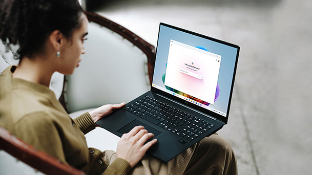Cette image montre une personne utilisant un ordinateur portable, dont l'écran affiche une interface colorée, avec un message sur l'autonomie prolongée de la batterie.
