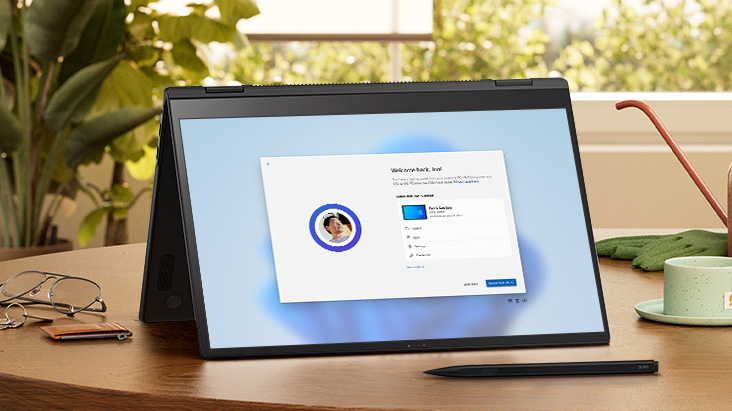 Cette image montre une tablette affichant un écran de configuration Windows 11 sur un bureau en bois, avec une plante, un cahier et un stylo à proximité, soulignant la facilité du transfert de fichiers.