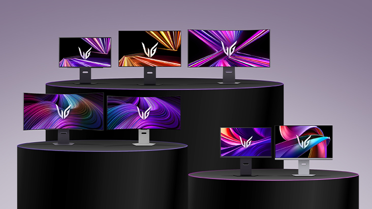 Une gamme de moniteurs LG UltraGear de différentes tailles et conceptions, présentés sur des estrades noires à plusieurs niveaux, chaque écran affichant des graphiques abstraits aux couleurs vives dans les tons violet, orange et rose.