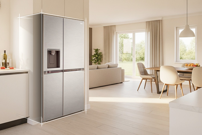 Bright beige-toned kitchen interior with a silver LG fridge freezer built into the left side. On the right, a dining table with flowers placed on top completes the scene.