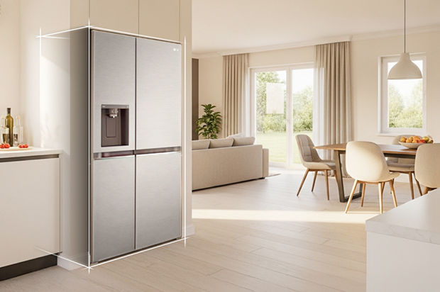 Bright beige-toned kitchen interior with a silver LG fridge freezer built into the left side. On the right, a dining table with flowers placed on top completes the scene.	