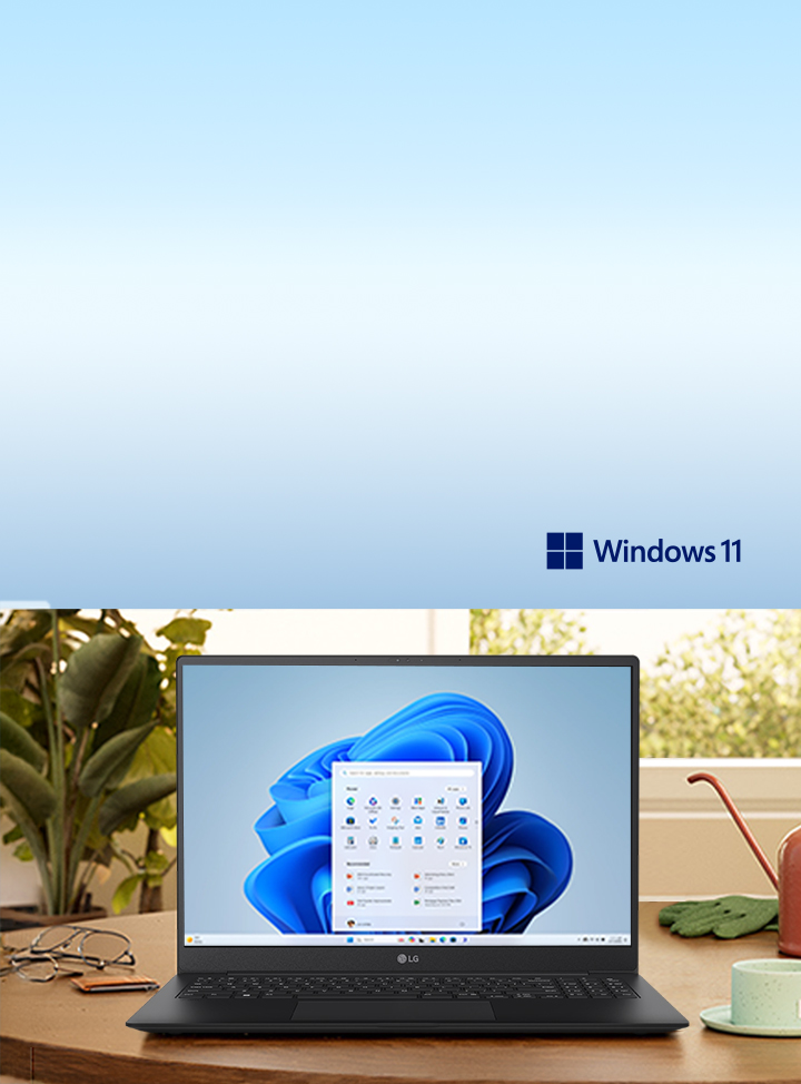This image shows a laptop with Windows 11 displayed on a wooden desk, surrounded by plants and a lamp, evokes a serene workspace.