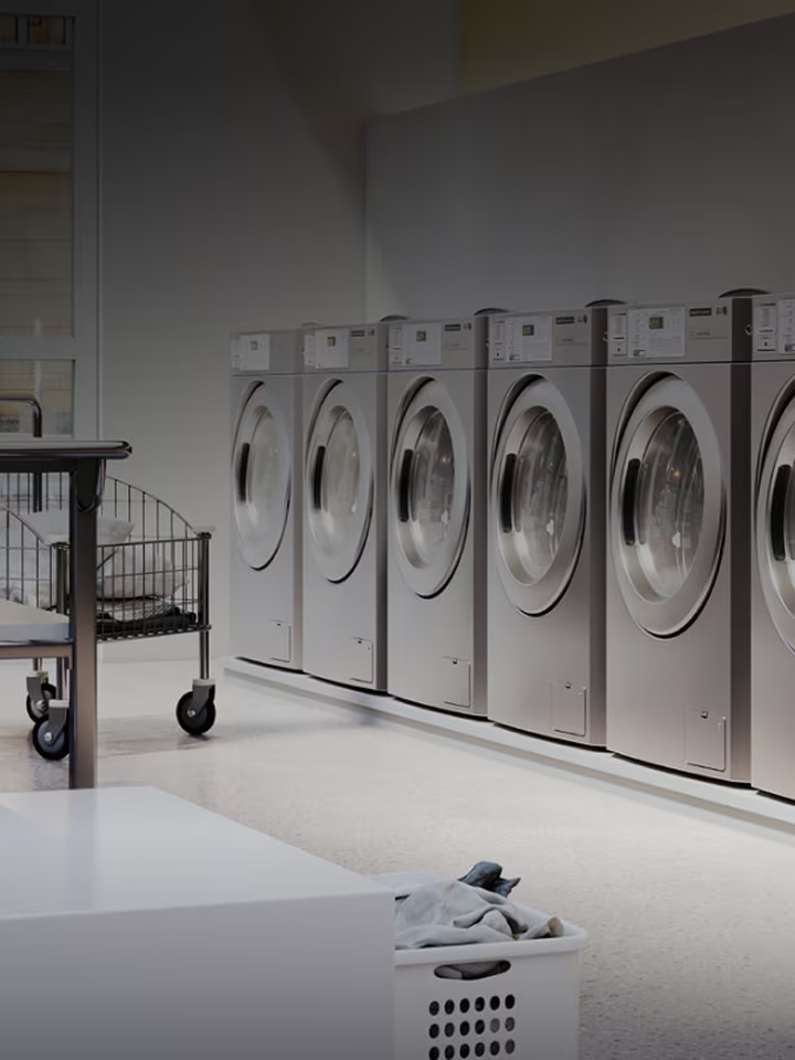 Commercial laundry room with multiple stainless steel washers lined up in a clean, modern space	