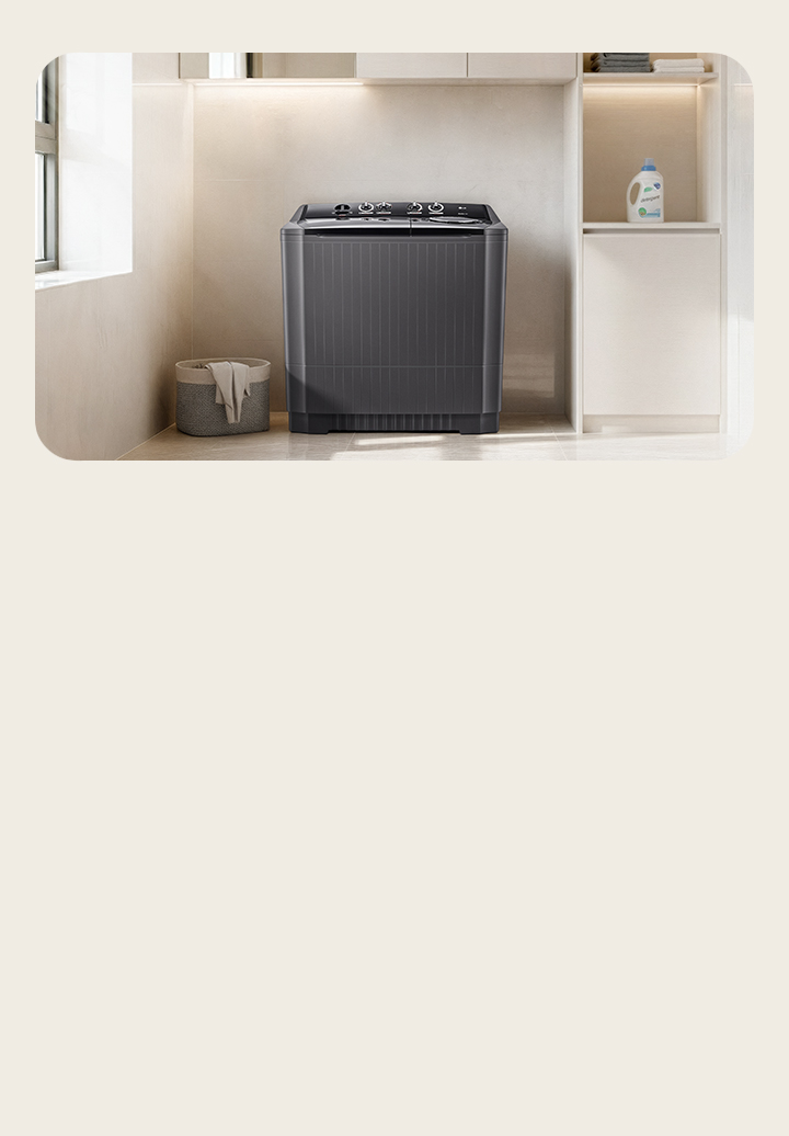There is a twin washing machine in the center of a modern multipurpose room with a wide light brown interior. The light comes from the left window, and there is detergent on the right shelf.