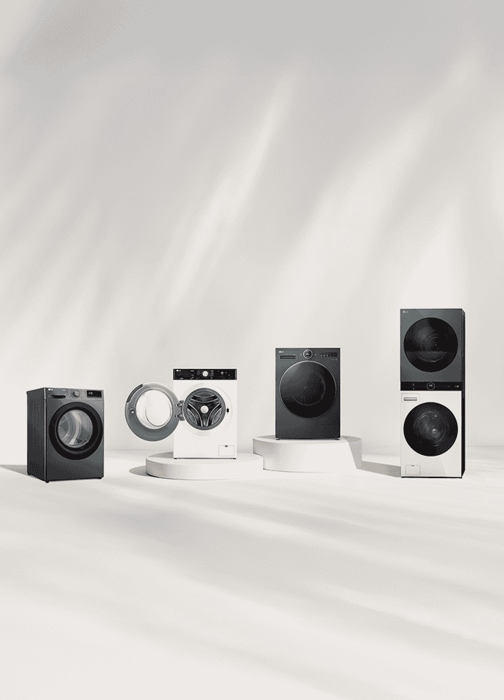 LG washer and dryer lineup in front of a beige wall. Includes a tumble dryer, front load washer with open door, washer dryer combo, and WashTower. A forest view is visible on the right.