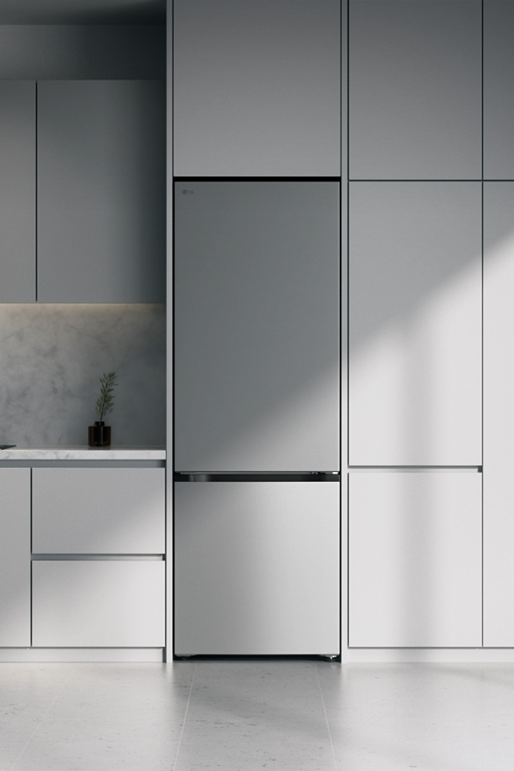 LG silver fridge freezer sliding into modern minimalist kitchen cabinetry in a modern gray kitchen with a stone backsplash.	