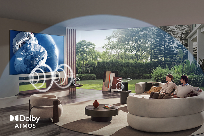 LG OLED evo AI C6 with Dolby Atmos displays a wide space scene in a living room, with graphic sound waves surrounding viewers and speakers to indicate immersive, multi-directional, object-based audio.