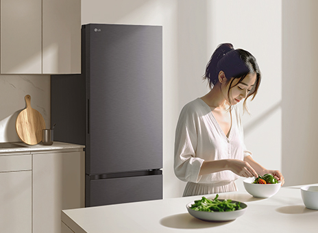 White LG 2-door Freezer in a Modern Kitchen. A woman has breakfast at a table with food.	