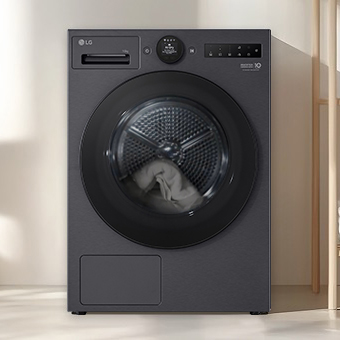 LG black tumble dryer installed under a counter in a laundry area. The transparent door shows laundry inside, clearly visible through the front of the machine.