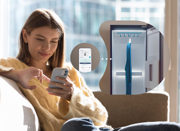 A woman sitting on the sofa with her cell phone while the LG Styler is working