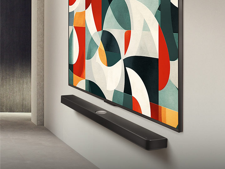 Slightly angled view of LG QNED TV mounted on a wall above a LG Soundbar in a modern living space. LG QNED TV depicts an abstract background in green, white, red and orange.