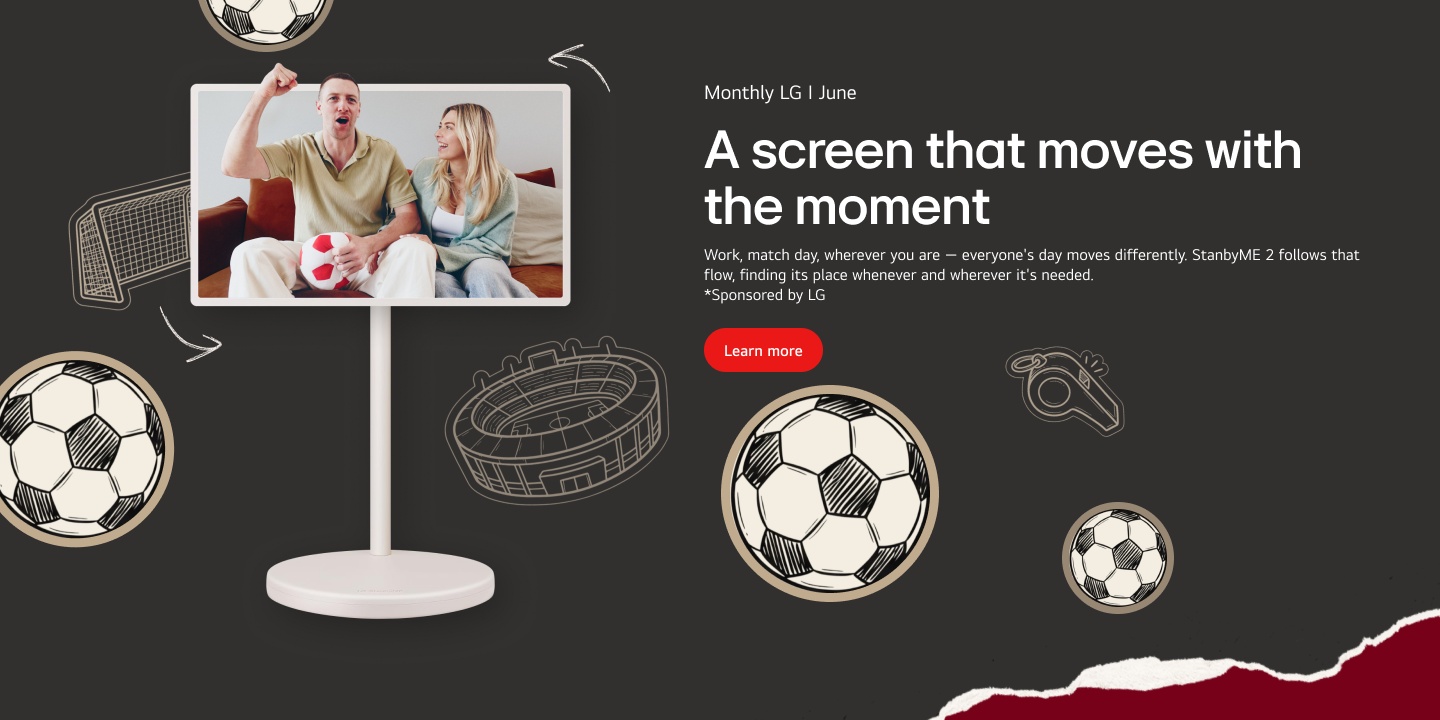 On the screen of the StanbyME 2, a couple is sitting on the sofa; the man is holding a plush soccer ball and cheering with a raised fist, while the woman smiles next to him.