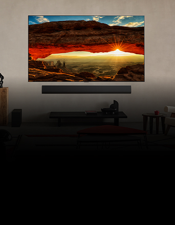 A wall-mounted OLED evo TV displays a vivid sunset through a red rock arch in a modern living room.