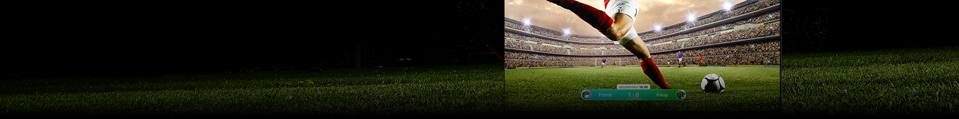 An image of an LG OLED showing a soccer game with a player in a red strip about to kick the ball across the stadium. The game score is visible at the bottom of the screen. The green grass from the pitch stretches beyond the screen to the black backdrop.