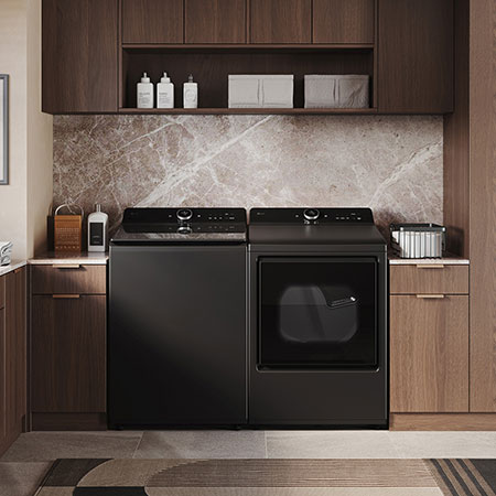 The LG Top Load Washer and Dryer set (DLEX8600BE) in Black Steel, showcasing the flat-top design and premium finish integrated perfectly beneath the upper cabinetry.