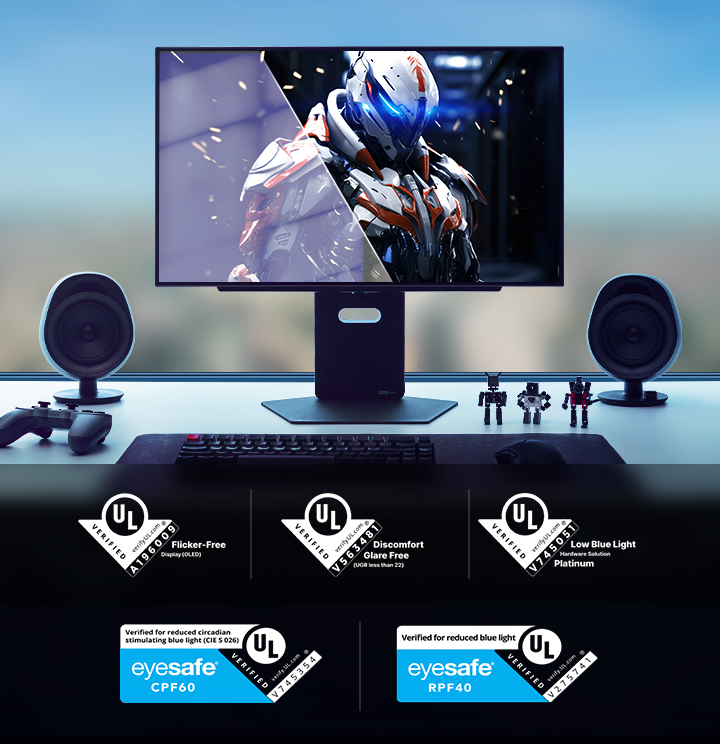 A futuristic desktop gaming setup with a large monitor displaying a sci-fi armored character. The desk features a controller, speakers, mechanical keyboard, and action figures. Multiple UL and Eyesafe certifications for flicker-free, glare-free, low blue light, and eye safety are shown at the bottom of the image.