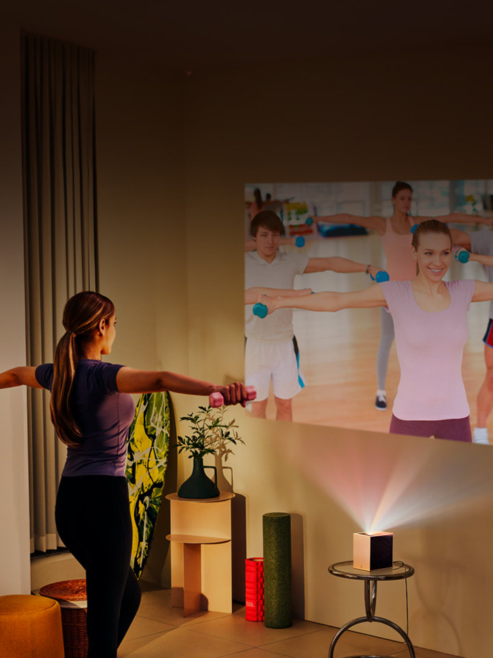 Woman doing yoga with LG CineBeam projection in the background.