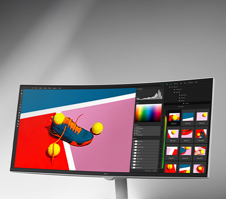 Curved monitor displaying a vibrant winter scene of two people in orange snow gear, shown within a photo editing software interface with color and histogram tools, emphasizing sRGB 99% and HDR support.