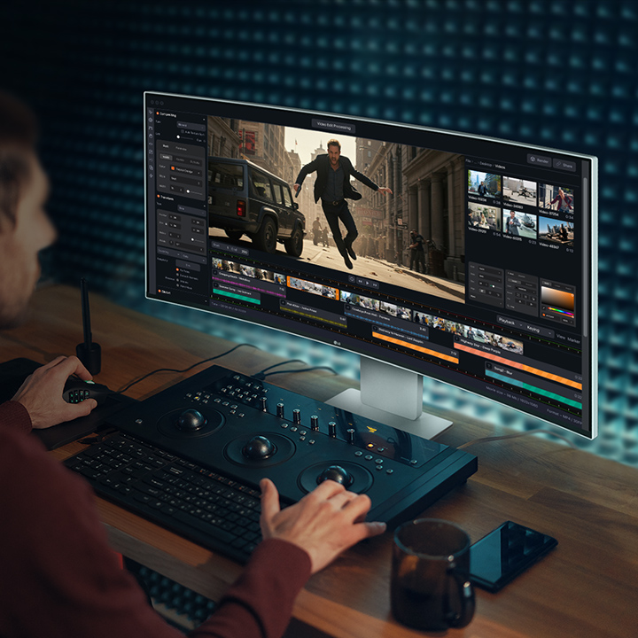 A guy is working with a video-creating program on UltraFine Monitor.	