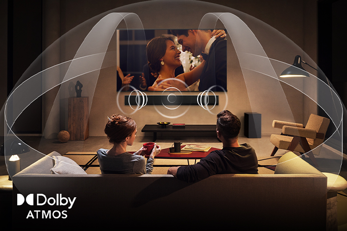 Salon confortable et faiblement éclairé où un couple regarde un film sur leur LG TV avec LG Soundbar. Graphiques montrant comment Dolby Atmos rempli l’espace d’un son multicanal. Dolby Atmos au coin.