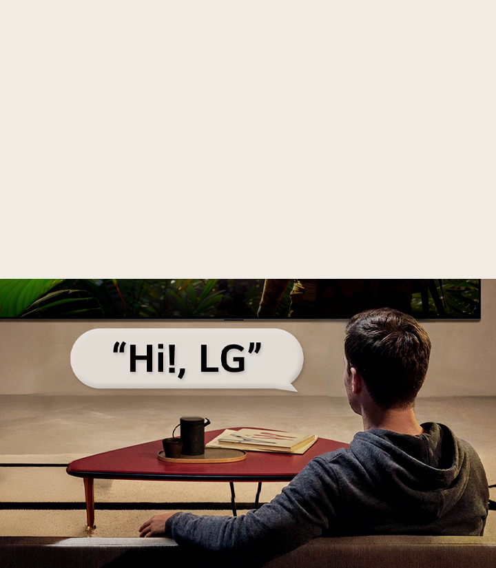Personne dans son salon. Bulle de conversation autour d’eux montrant comment ils interagissent avec leur LG TV en disant simplement « Hi LG ».
