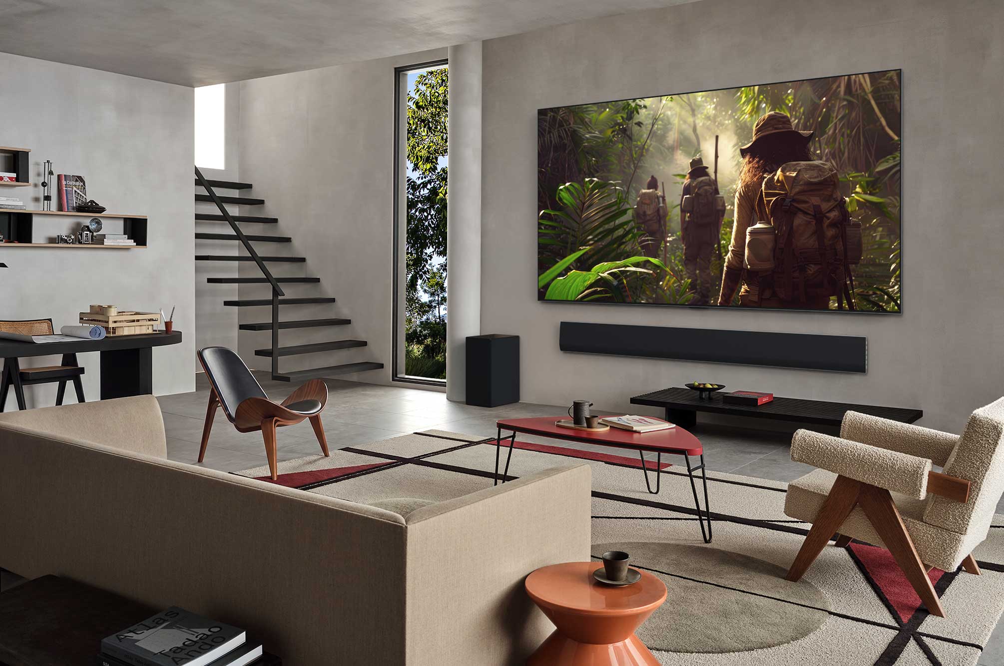 Vue large d’un salon à l’intérieur d’une maison haut de gamme, un homme regarde un film sur son LG OLED TV fixé au mur. La conception du téléviseur s’intègre élégamment au mur et à la décoration intérieure.