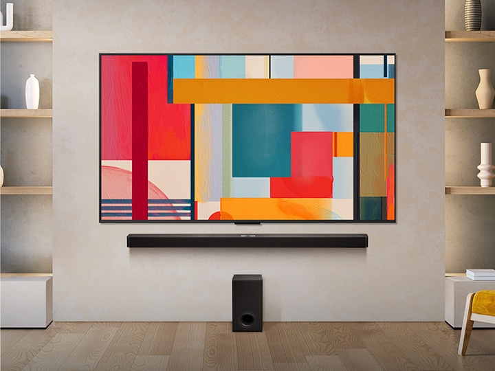 LG QNED TV monté sur un mur au-dessus d’une LG Soundbar dans un salon moderne. LG QNED TV représente un fond abstrait en vert, rouge et orange.