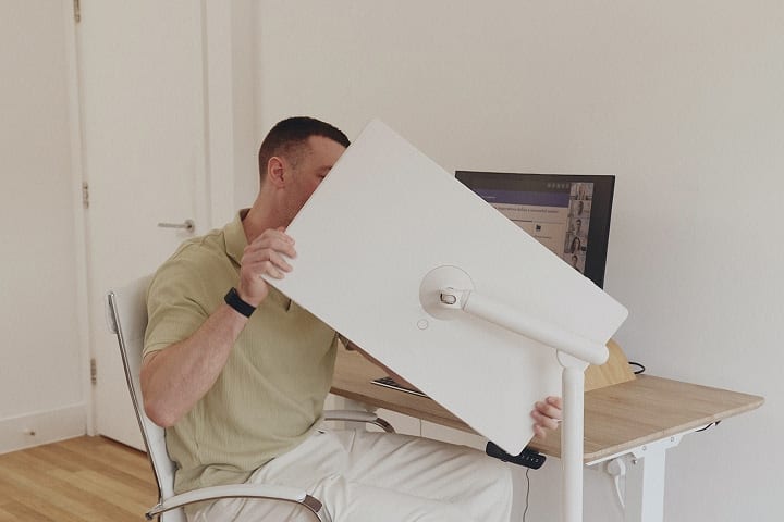 Un homme assis sur une chaise faisant pivoter un écran intelligent StanbyME 2 à un angle de 45 degrés.