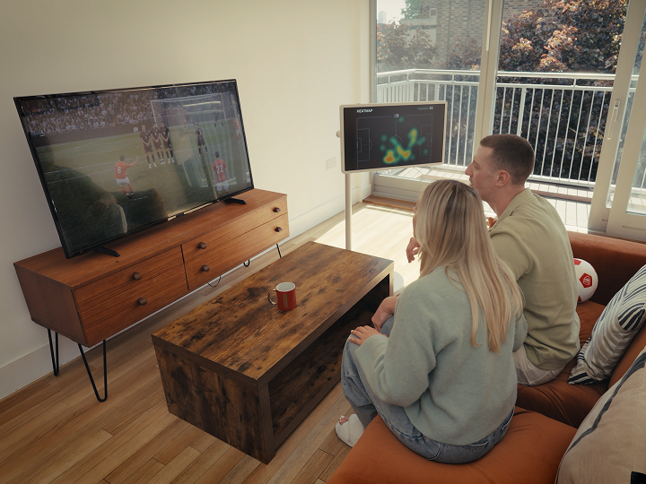Un couple regarde le football à la télévision dans le salon, tandis qu'un StanbyME 2 affiche une carte thermique à côté d'eux.