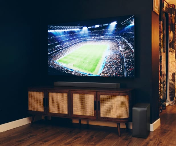 Un téléviseur fixé au mur sur un meuble en bois affichant une scène vivante de stade de football