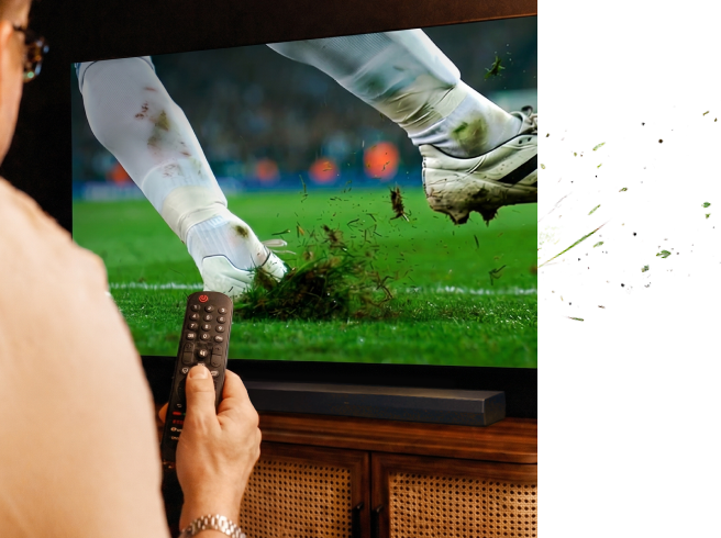 Une main tenant une télécommande tout en regardant un match de football sur une TV