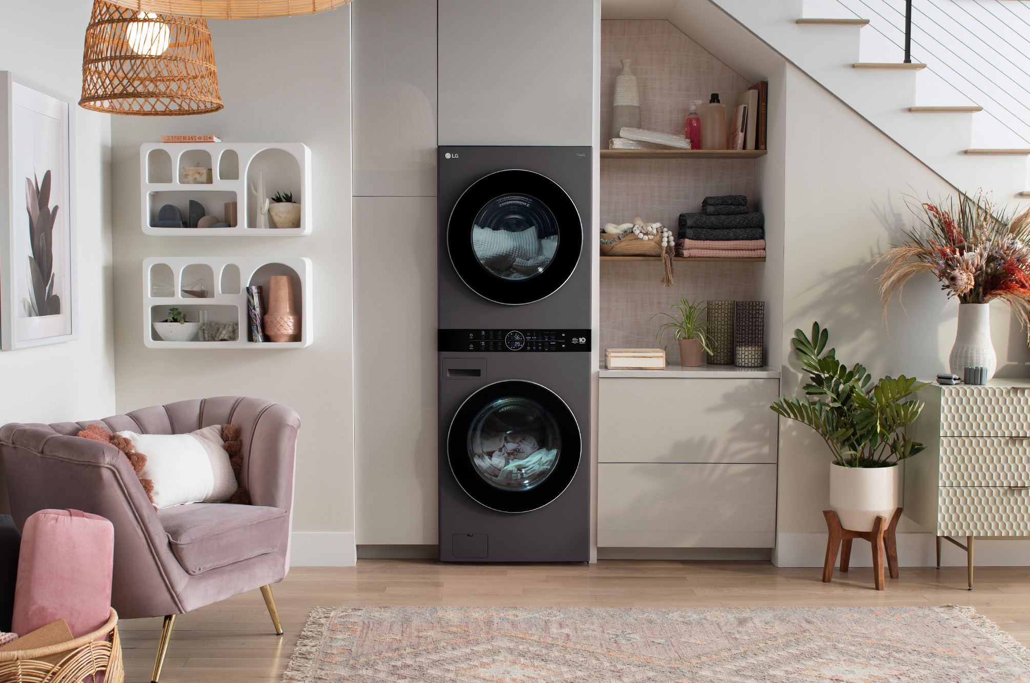 Le LG WashTower WKHC252HBA en Noir Acier, illustrant son design haut de gamme et son installation peu encombrante, intégré harmonieusement sous un escalier dans un espace de vie moderne.