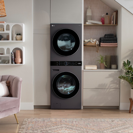 Le LG WashTower WKHC252HBA en Noir Acier, illustrant son design haut de gamme et son installation peu encombrante, intégré harmonieusement sous un escalier dans un espace de vie moderne.