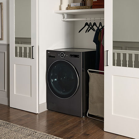 Le lave-linge séchant frontal LG WM6998HBA en Noir Acier, illustrant son design tout-en-un peu encombrant et son installation discrète dans un placard.