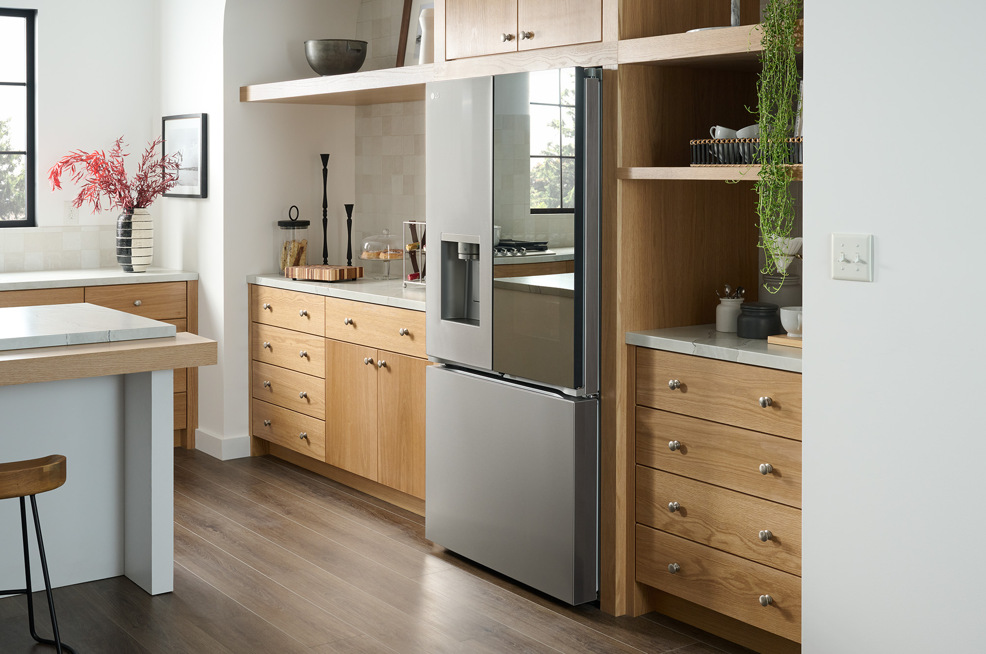 Le réfrigérateur à portes françaises LG LRYKC2606S de 36 po et 26 pi³ au fini inoxydable, présenté dans une cuisine moderne avec armoires en bois clair.