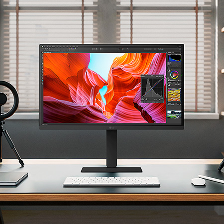 Moniteur LG 27U730A au fini sombre placé au centre d'un studio professionnel éclairé, affichant un logiciel d'étalonnage pour l'édition précise de photos et vidéos.