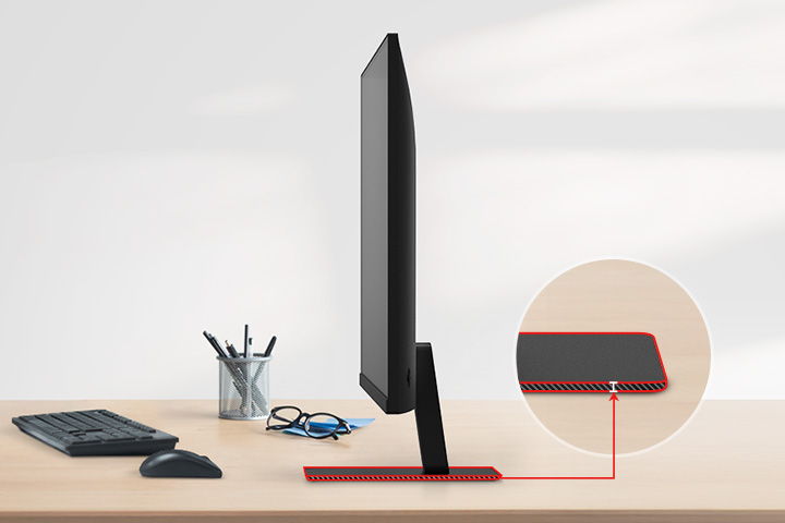 Un moniteur QHD avec un support ultra-fin sur le bureau, avec un porte-crayon, des lunettes, un clavier et une souris à côté.