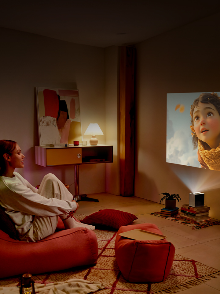 Femme regardant un film avec un projecteur LG CineBeam.
