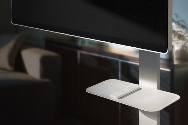 Support TV Swing Stand avec Swing Stand Plate intégrée, tenant une télécommande, placé dans un environnement de salon moderne.