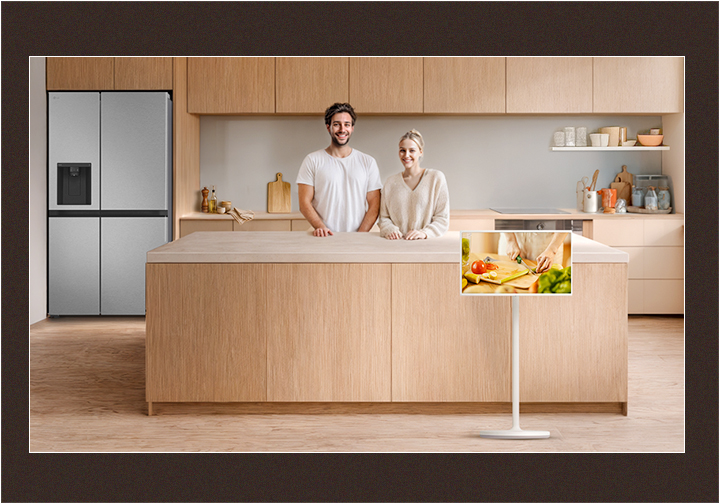 Image d'une cuisine nette et d'un couple regardant droit devant eux avec de joyeux sourires.