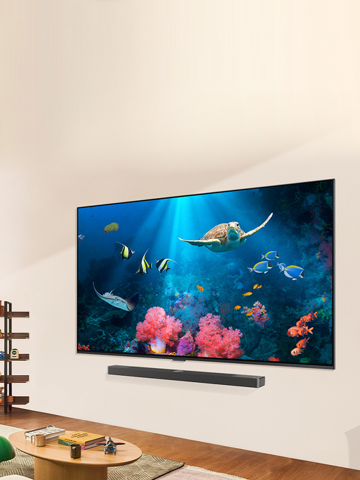 عائلة تشاهد مشهدًا مائيًا مشرقًا على تلفزيون LG QNED مع LG Soundbar، في غرفة معيشة مشرقة وطبيعية.