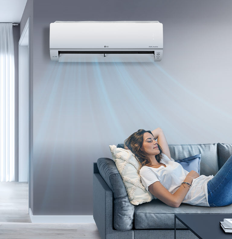 تتمدد سيدة على أريكة في غرفة معيشة بها مكيف هواء LG معلقًا على الجدار. تنبعث تيارات الهواء، الموضحة باللون الأزرق في الصورة.