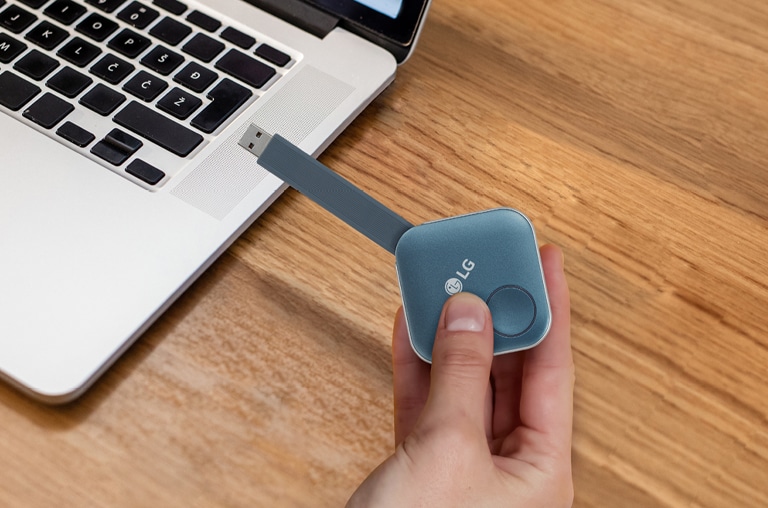 بعد الاقتران، يمكنك مشاركة الشاشة مع لافتة إل جي عن طريق توصيل جهاز دونجل USB بالحاسوب الشخصي. صورة يظهر بها شخص يحمل دونجل USB ويحاول توصيله بالحاسوب الشخصي.