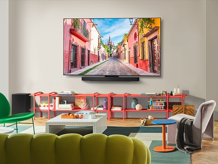 Wide view of a living room inside a premium home, a couple is watching a movie on their wall-mounted LG OLED TV. The TV's design blends elegantly with the wall and the interior design.