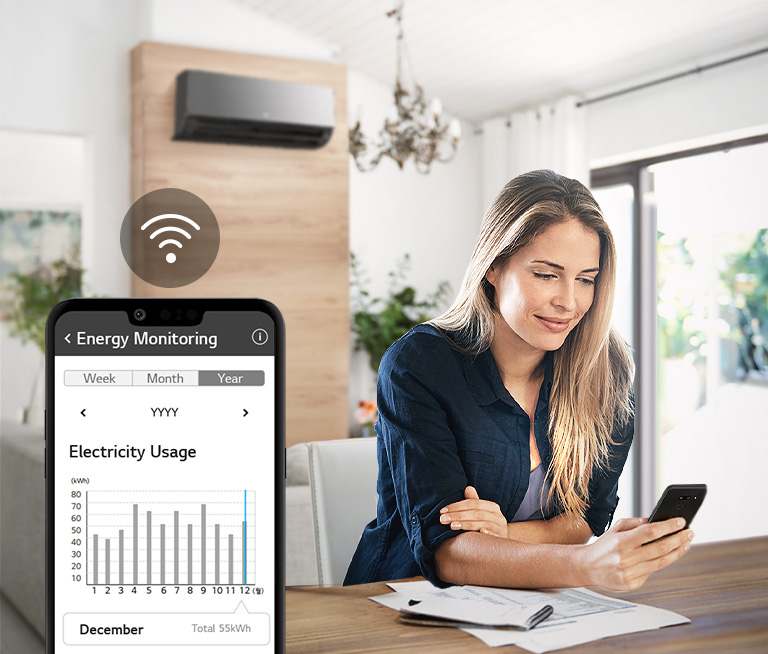 Woman sitting at table checks electricity usage on smartphone app while air conditioner is on, in bright living room.