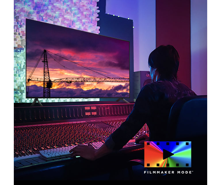 A man in a dark editing studio looking at an LG TV displaying the sunset. On the right bottom of the image is a FILMMAKER Mode logo.