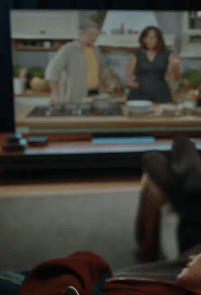 A man and a woman are on the sofa, watching a soccer broadcast on an LG TV in the living room. The scene transitions, and the man and woman are hugging. The camera focuses on the LG XBOOM next to them.