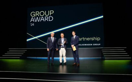 A picture of three men smiling on stage at Volkswagen Group Award 2024