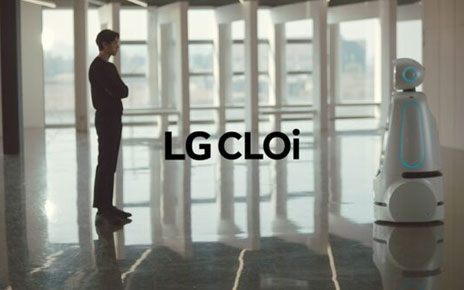 The LG CLOi robot designed to assist humans in public spaces standing face-to-face with a man in a building lobby.